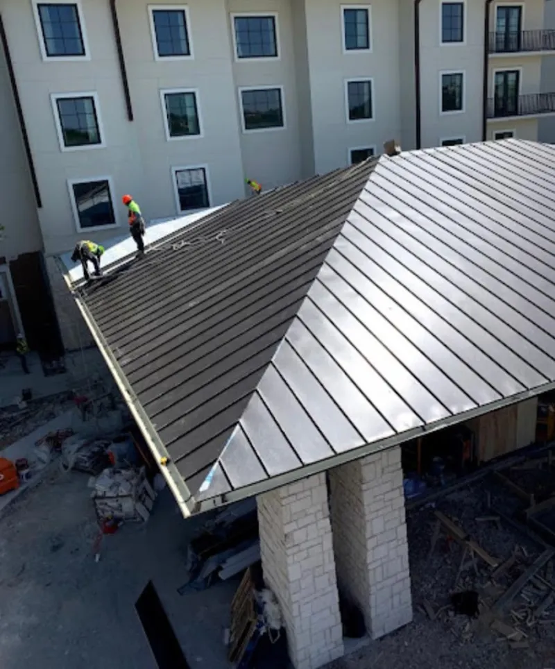 Crew installing standing seam metal roof panels on a commercial project in St. Francis
